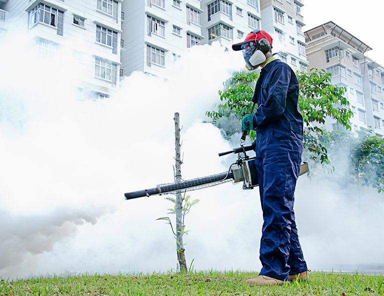 A pest control technician operating a fogging machine outdoors for mosquito or pest control by Sac Pest Pros in Sacramento, CA.