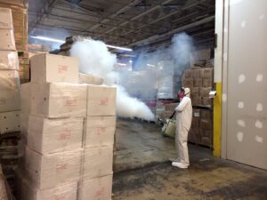 A pest control technician in a hazmat suit fogging a warehouse for pest extermination by Pest by MD in Jersey City, NJ.