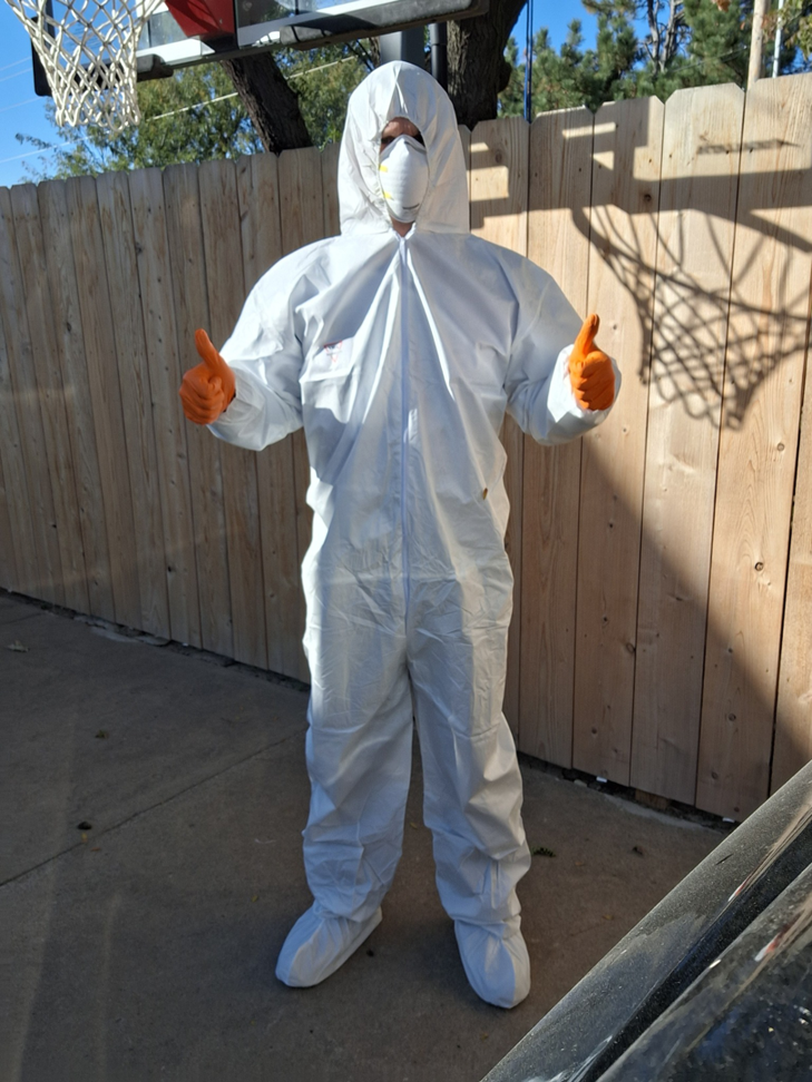 A Howe Pest Management technician in Manhattan, KS, wearing a full hazmat suit and respirator, ready for a pest control job.
