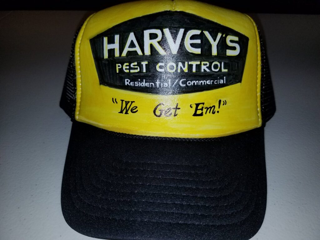 A pest control technician in a hazmat suit and respirator standing next to a Harvey's Pest Control truck in Los Angeles, CA.