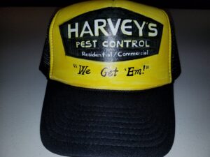 A pest control technician in a hazmat suit and respirator standing next to a Harvey's Pest Control truck in Los Angeles, CA.