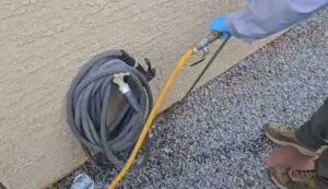 A pest control technician's gloved hand holding a spray hose for treatment at Bye Bye Bugs Pest Control in Indianapolis, IN