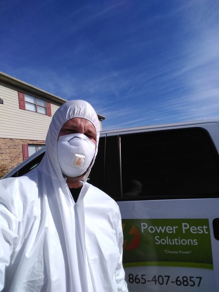 A pest control technician in a protective hazmat suit and respirator mask from Power Pest Solutions in Knoxville, TN.
