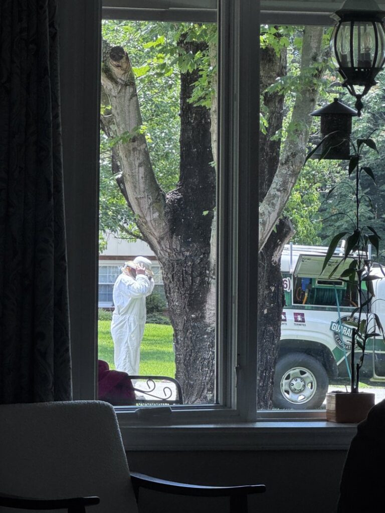 A Bulwark Exterminating technician wearing protective gear at a residential job site in Greensboro, NC.