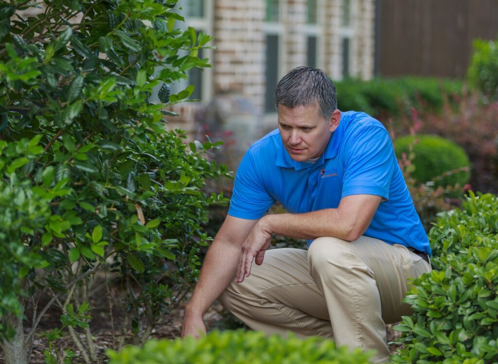A Berrett Pest Control Denver technician inspecting a garden area for pests outside a home in Denver, CO.