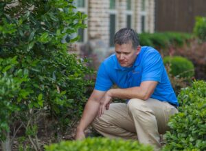 A Berrett Pest Control Denver technician inspecting a garden area for pests outside a home in Denver, CO.