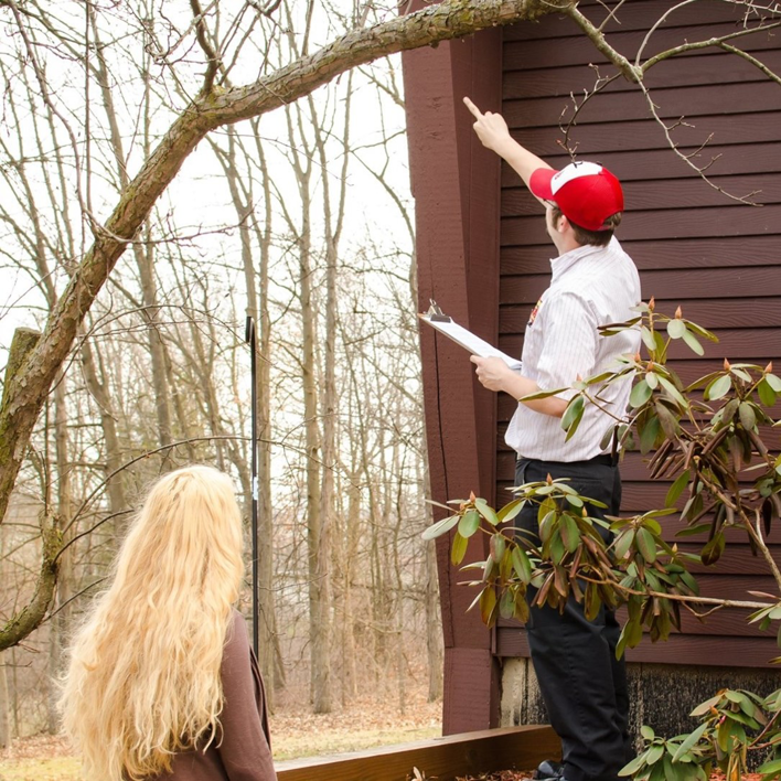 A pest control technician inspecting the exterior of a house for Arab Pest Control in Evansville, IN.