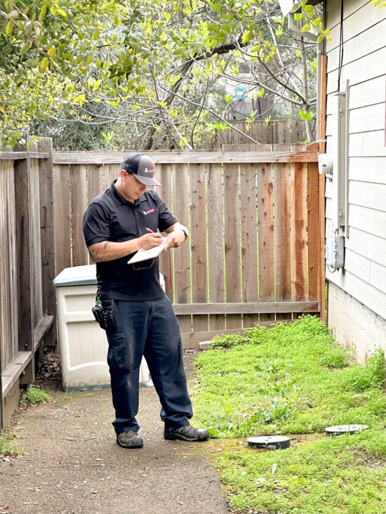 A pest control technician from Aantex Pest Control Norcal inspecting an outdoor area in Sacramento, CA.