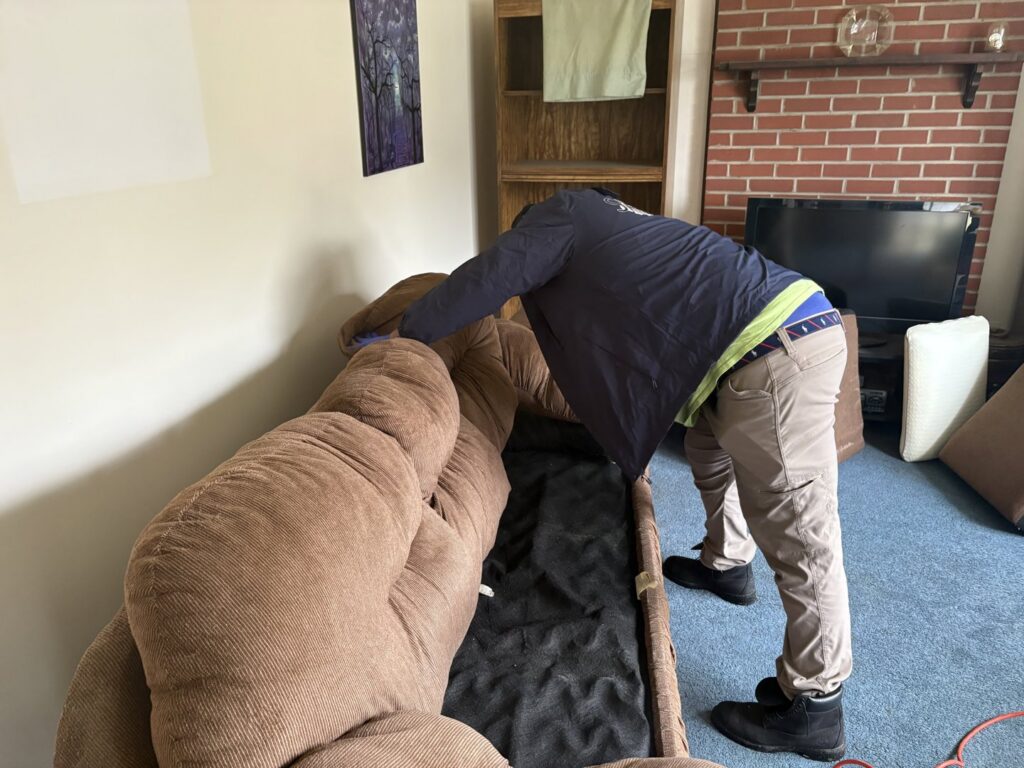 A SanPro Pest Control VA technician inspecting a sofa for pests during a job in Richmond, VA.