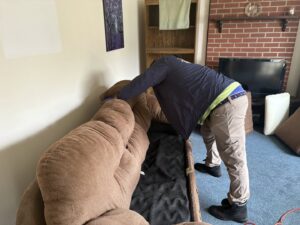 A SanPro Pest Control VA technician inspecting a sofa for pests during a job in Richmond, VA.