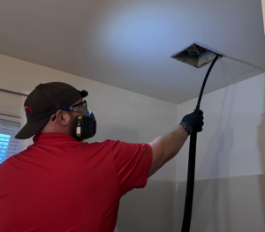 A pest control technician inspecting a ceiling vent with a hose tool at Dominion Pest Control LLC in Lancaster, PA.