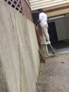 A pest control technician on a ladder inspecting an exterior wall for pests at a property in Louisville, KY, by A-1 Pest Control, Inc.