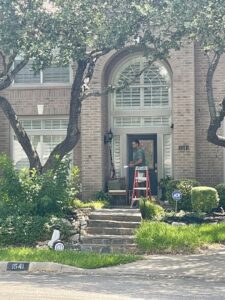 A Hawx Pest Control technician on a ladder performing pest treatment or inspection on a house in San Antonio, TX.