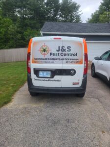 A J&S Pest Control technician on a ladder performing pest treatment on a house in Coventry, RI.
