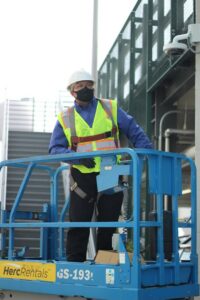 A Pestec technician on a scissor lift wearing a mask and safety gear for pest control in San Francisco, CA.