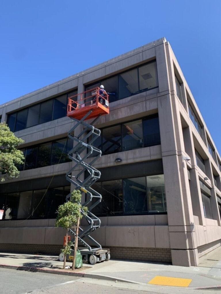 A Pestec technician on a scissor lift performing exterior pest control work on a building in San Francisco, CA.