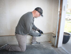 An Upfront Pest technician placing a pest bait station inside a garage in North Kansas City, MO.