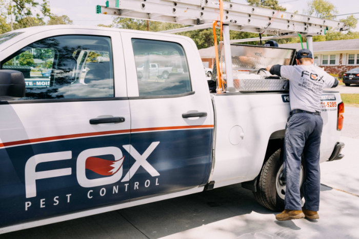 A Fox Pest Control technician preparing equipment from a company truck in Glen Ellyn, IL