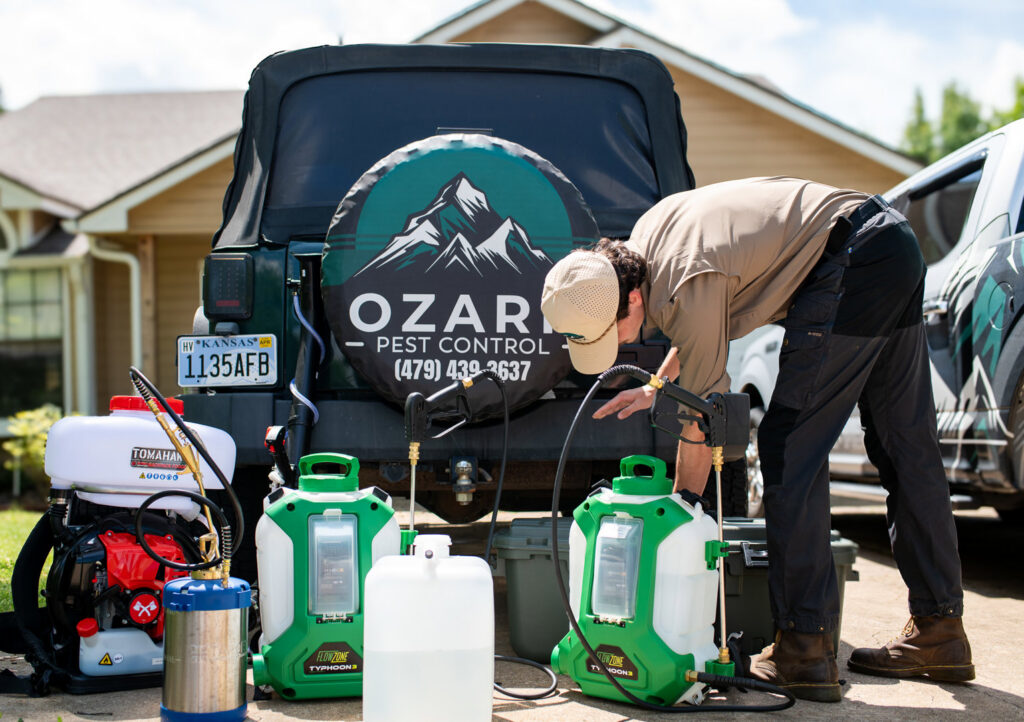 A pest control technician preparing sprayers and equipment for a job at Ozark Pest Control in Fayetteville, AR.