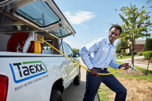 A HomeTeam Pest Defense technician preparing to spray, pulling a hose from a service truck in Longwood, FL.