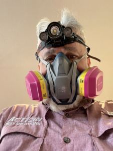 A pest control technician wearing a respirator mask and headlamp from Action Pest Solutions in Lowell, AR.