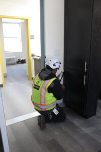 A Pestec technician sealing a potential pest entry point near a cabinet in San Francisco, CA.