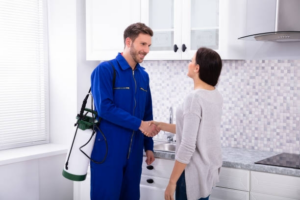 A pest control technician shaking hands with a client in a kitchen at Grenier's Pest Control in Essex Junction, VT.