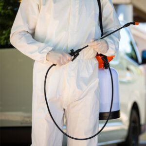 A pest control technician in a protective suit holding a sprayer, ready for service from Star Pest Control in Idaho Falls, ID.