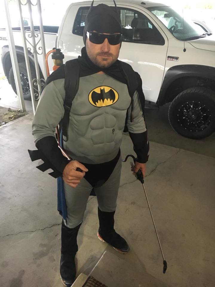 A pest control technician in a Batman costume holding a sprayer, ready for a job at Bakersfield Pest Control in Bakersfield, CA