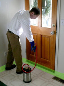 A pest control technician spraying a baseboard inside a home for Saela Pest Control in Hubbard, OR.