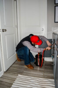 A pest control technician from Liberty Pest Services LLC spraying inside a bathroom cabinet in Mayflower, AR.