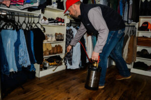 A pest control technician from Liberty Pest Services LLC spraying inside a closet for pest control in Mayflower, AR.