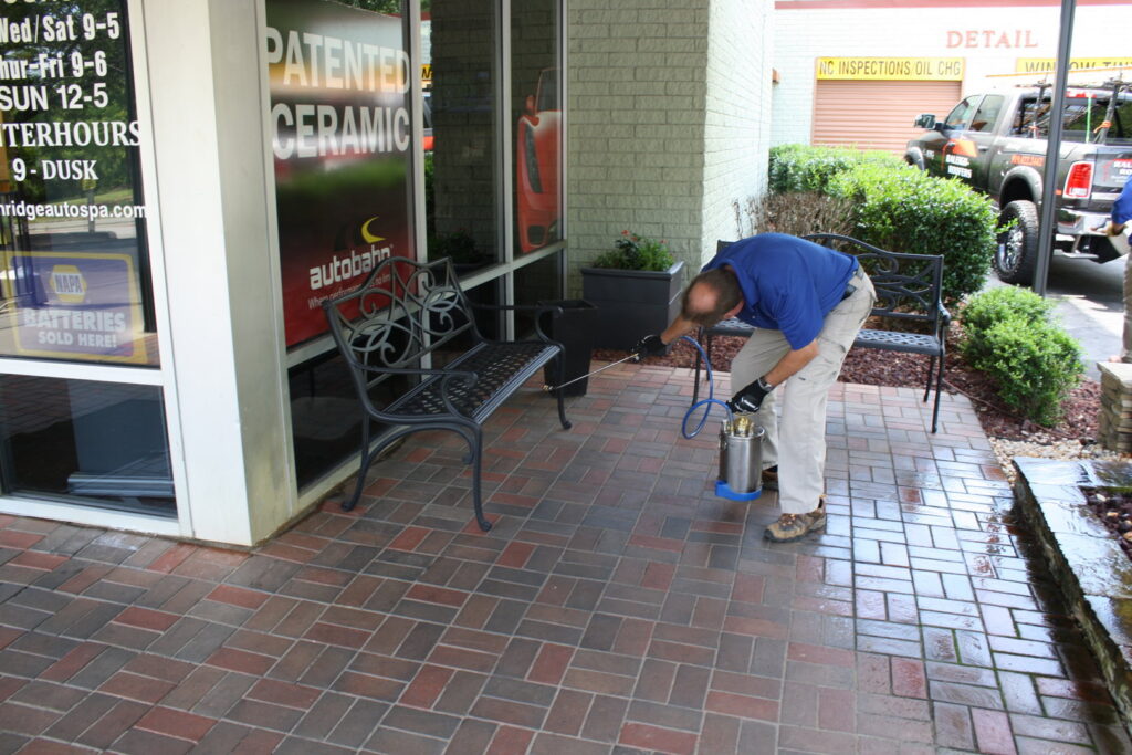A Capital Pest Services technician spraying a commercial patio area for pest control in Raleigh, NC.