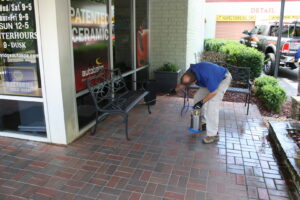 A Capital Pest Services technician spraying a commercial patio area for pest control in Raleigh, NC.