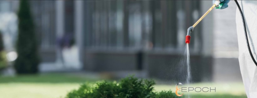 A pest control technician in protective gear spraying outdoors for Epoch Pest Solutions in Oklahoma City, OK.