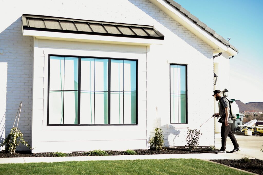 A Pallas Pest Control technician spraying the exterior of a house for pest treatment in Saint George, UT.