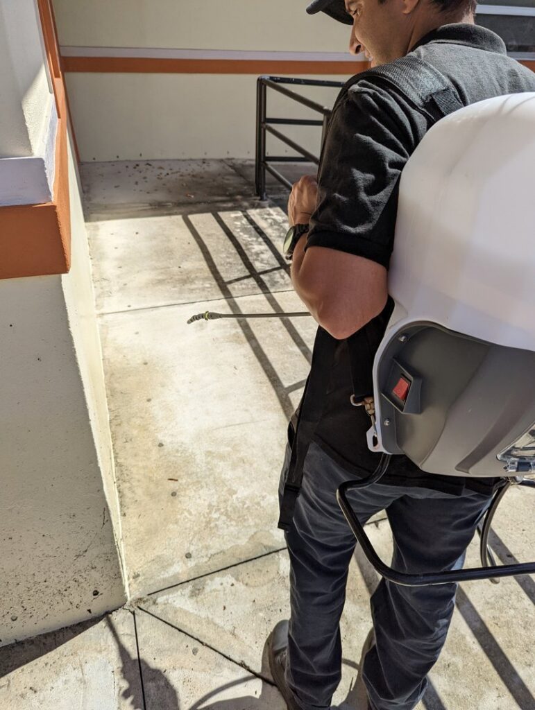 A pest control technician spraying the exterior of a building at Nexterminate in Hollywood, FL.
