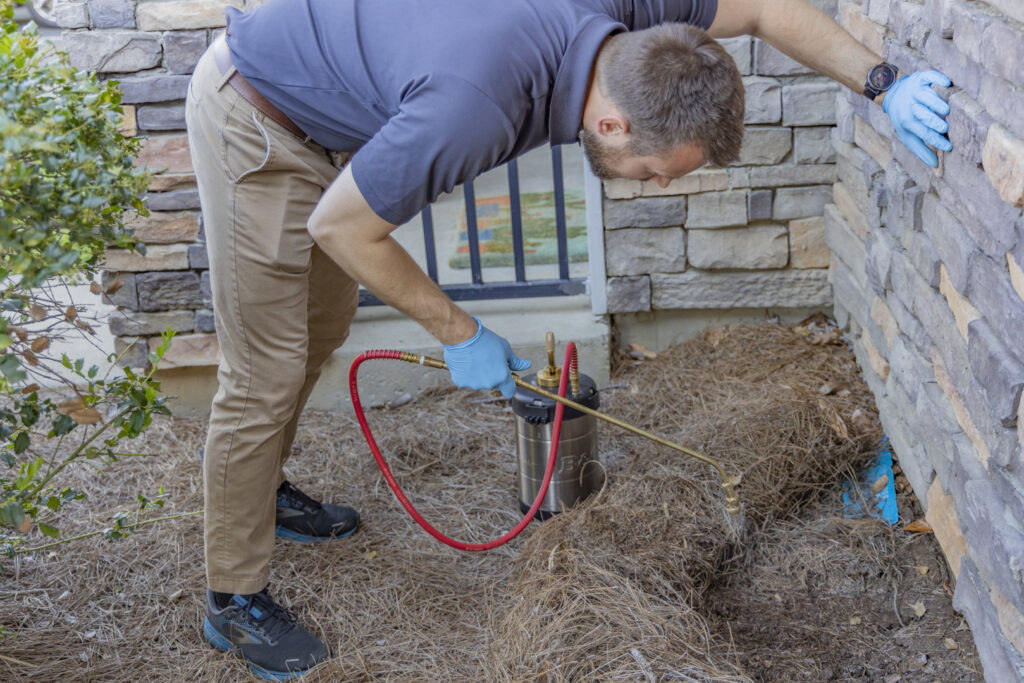 A Berner Pest Solutions technician applying pest control treatment to a building's foundation in Lexington, KY.