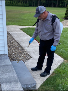 A Pest X Pro LLC technician spraying the exterior foundation of a home for pest control in Lewistown, PA.