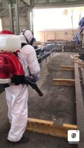 A pest control technician in a hazmat suit sprays the ground at a commercial property for Matar Termite & Pest Control in Alexandria, VA.