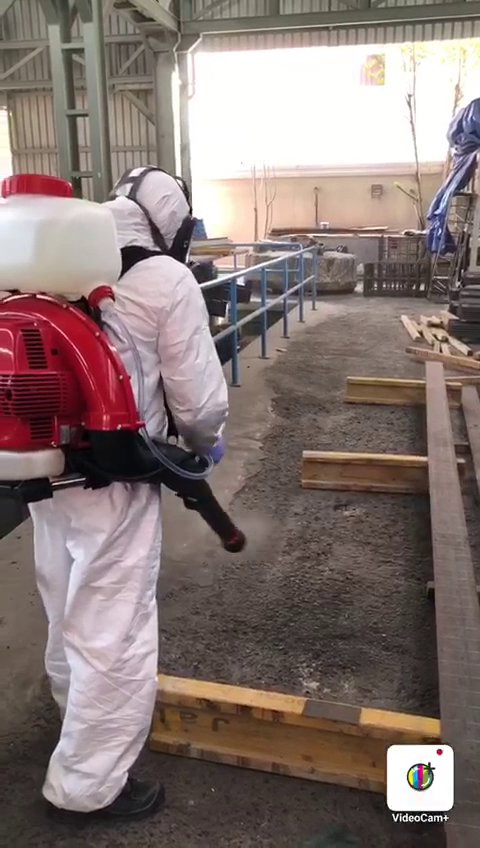 A pest control technician in a hazmat suit sprays the ground at a commercial property for Matar Termite & Pest Control in Alexandria, VA.
