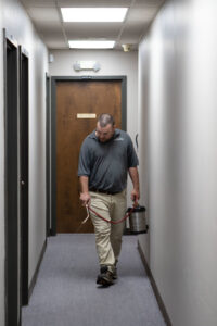 A pest control technician spraying a hallway for pest control at Southeastern Termite & Pest Control in Lake Worth, FL