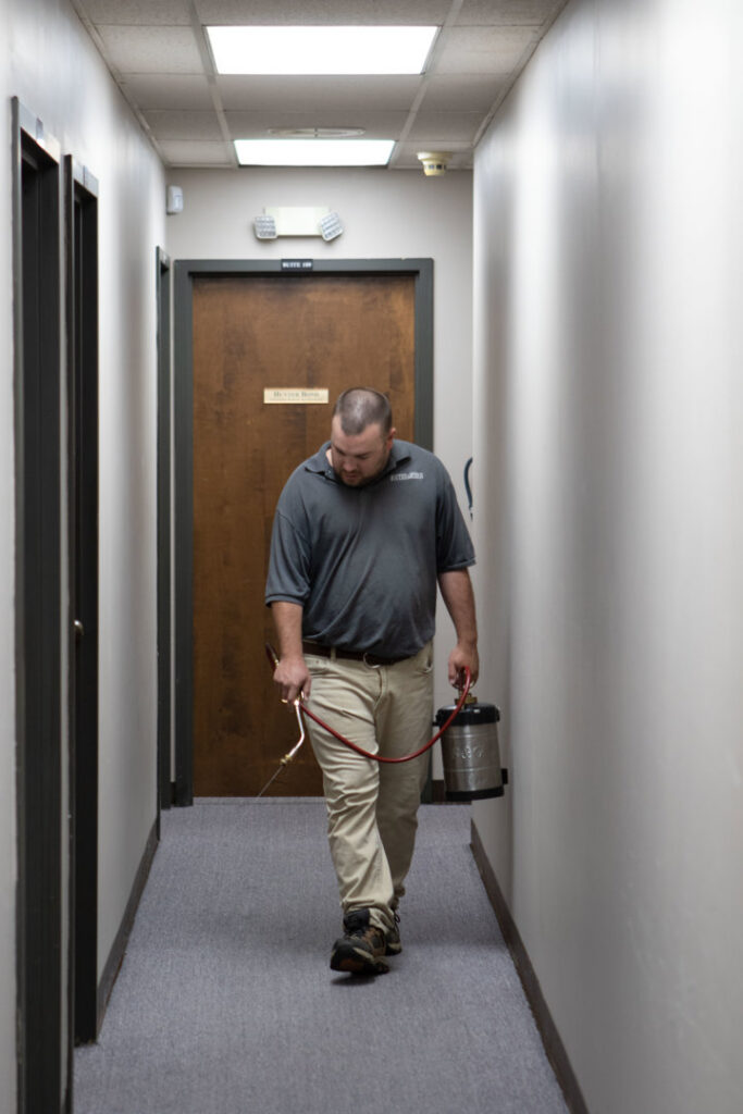 A pest control technician spraying a hallway for pest control at Southeastern Termite & Pest Control in Lake Worth, FL