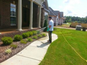 A pest control technician from A Plus Pest Control spraying the perimeter of a home in Huntsville, AL.