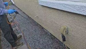 A pest control technician spraying the exterior of a house for pest treatment at Bye Bye Bugs Pest Control in Indianapolis, IN