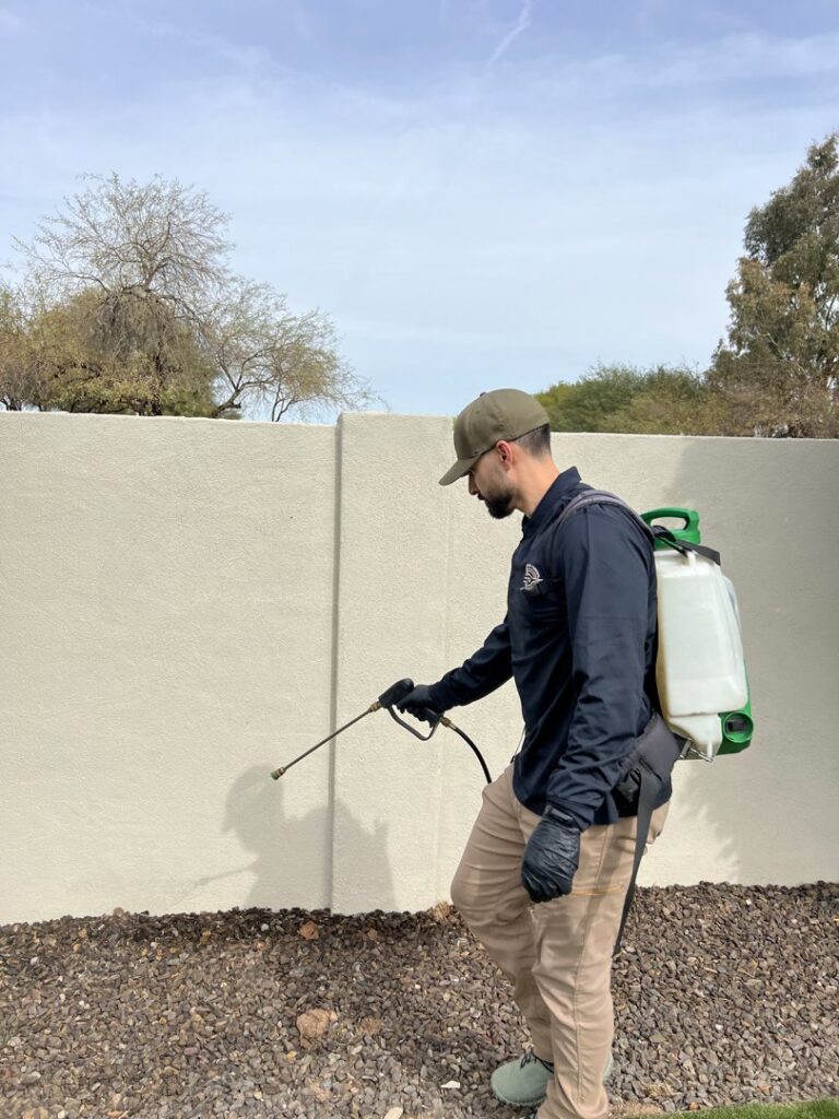 A CAPE Pest Control technician applying pest treatment to a house exterior in Mesa, AZ