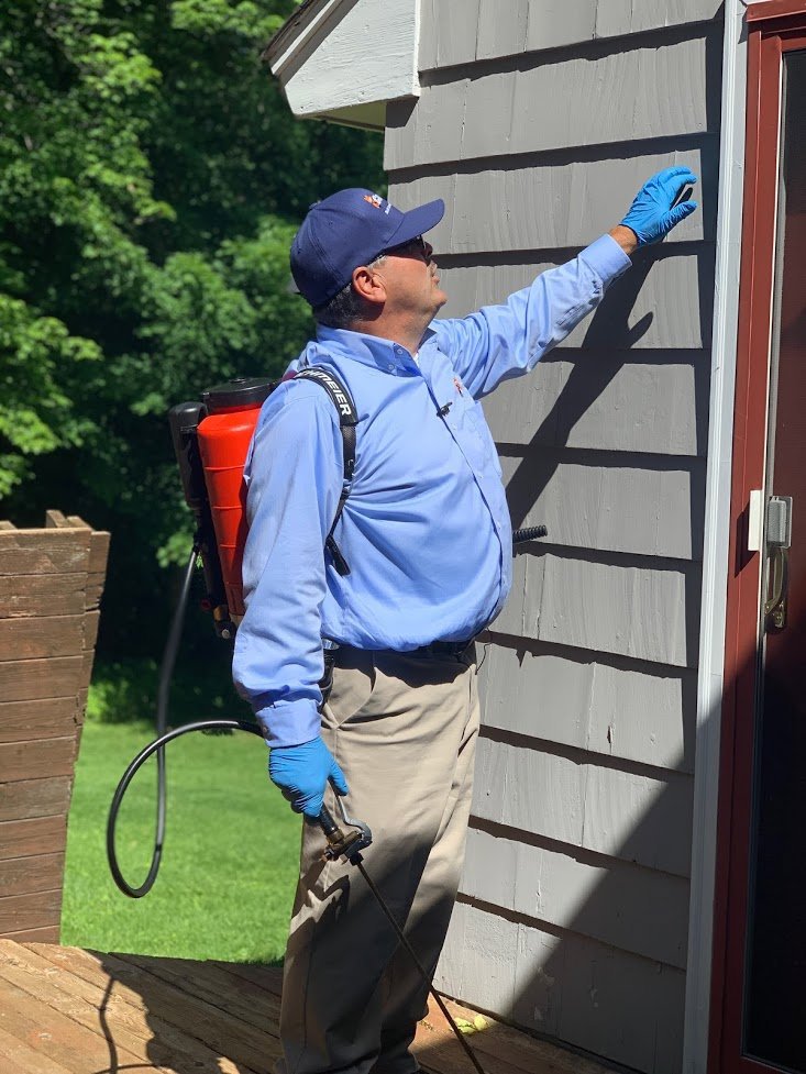 A Catseye Pest Control technician spraying the exterior of a residential home in Hartford, CT.