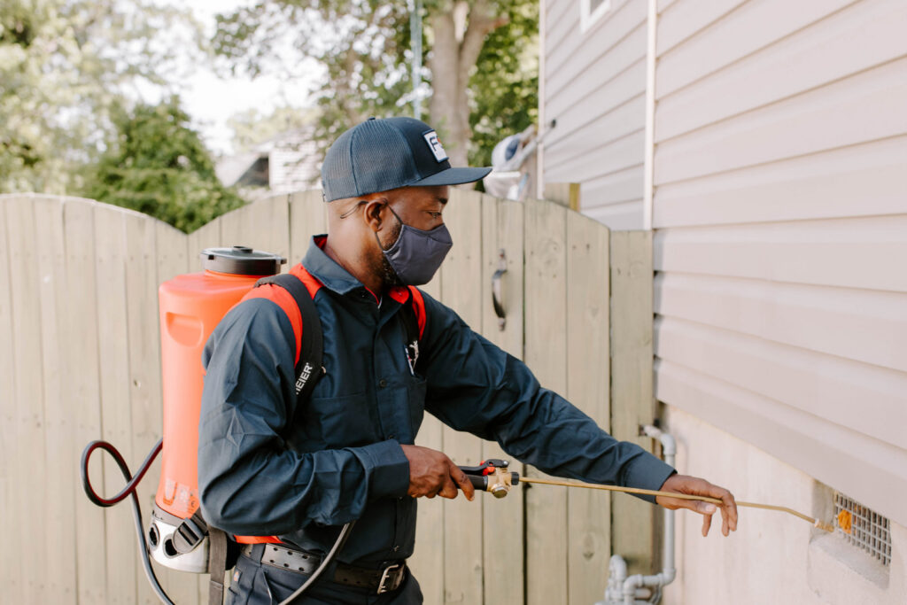 A Fox Pest Control technician spraying the exterior of a house for pest control in Glen Ellyn, IL