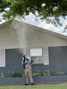 A Mosquito Malone Pest Control technician applying a mist treatment to a house exterior in Edmond, OK.