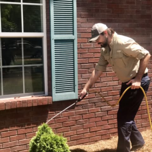 A Target Exterminating technician spraying the exterior of a brick house for pest control in Montgomery, AL.